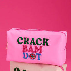 Three pink-themed zip pouches arranged on a bright pink background with scattered mahjong tiles and dice. The top pouch is light pink with embroidered text reading 'CRACK BAM DOT', the middle pouch is pale pink with 'MAIJ' embroidery, and the bottom-left pouch is pink with a green-and-white mahjong pattern.