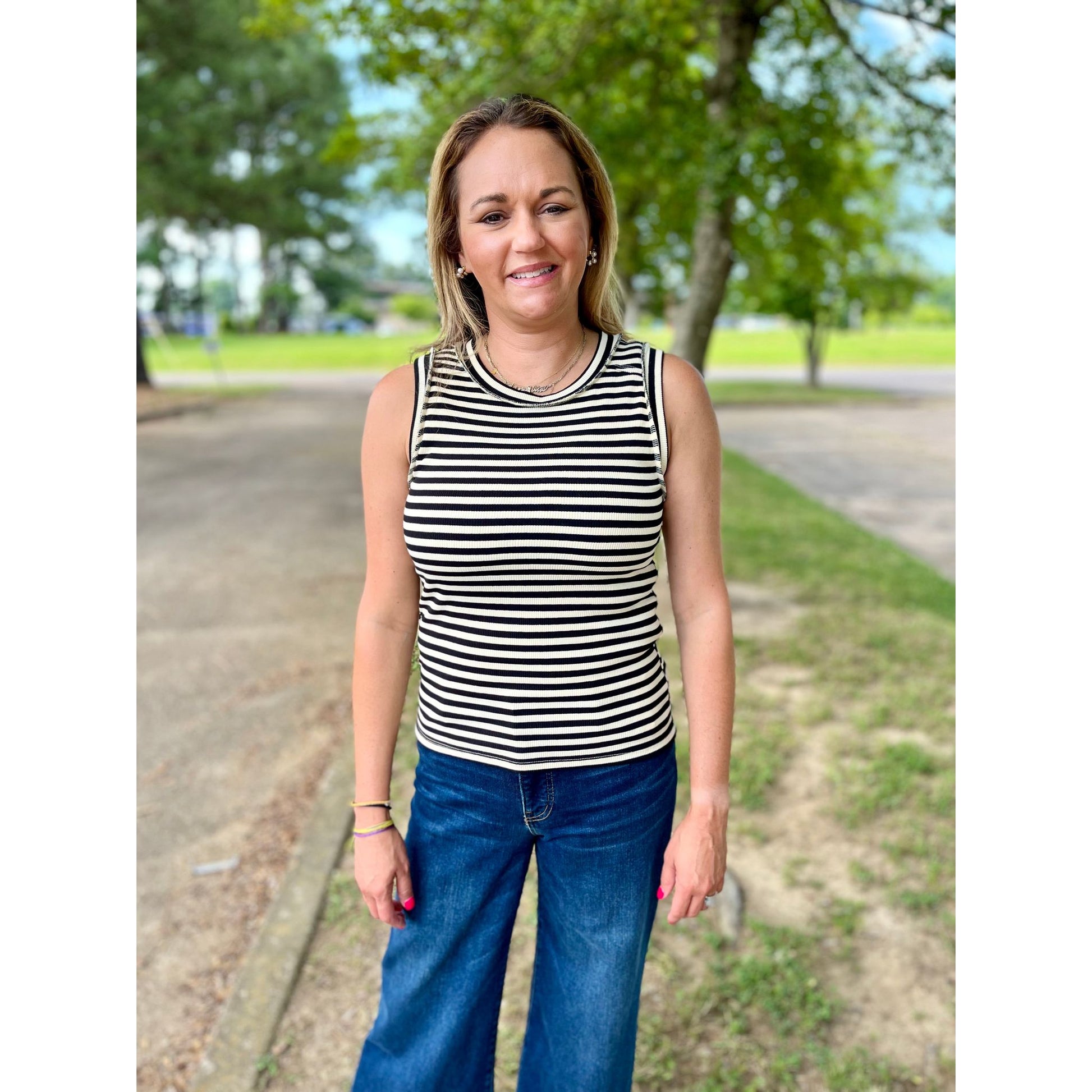 Effortlessly elevate your summer style with our Merrily Top! This striped tank top features a ribbed texture that adds a touch of sophistication to any outfit. Perfect for warm weather, it's also great for layering during cooler days. Upgrade your wardrobe with this versatile and stylish top.  Olivia is wearing a size small.