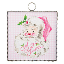 A square Christmas ornament with a scalloped silver metal border and a hanging loop at the top. The ornament features a watercolor-style illustration of Santa Claus with a fluffy white beard, pink hat, and green holly accents on a light pink gingham background, with 'Merry Christmas' written in pink script.