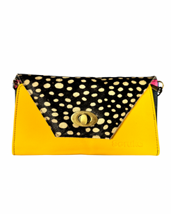 A color-blocked clutch bag with a bright yellow front and sides, a black flap decorated with beige cowrie shells, and a gold-tone turn-lock closure.