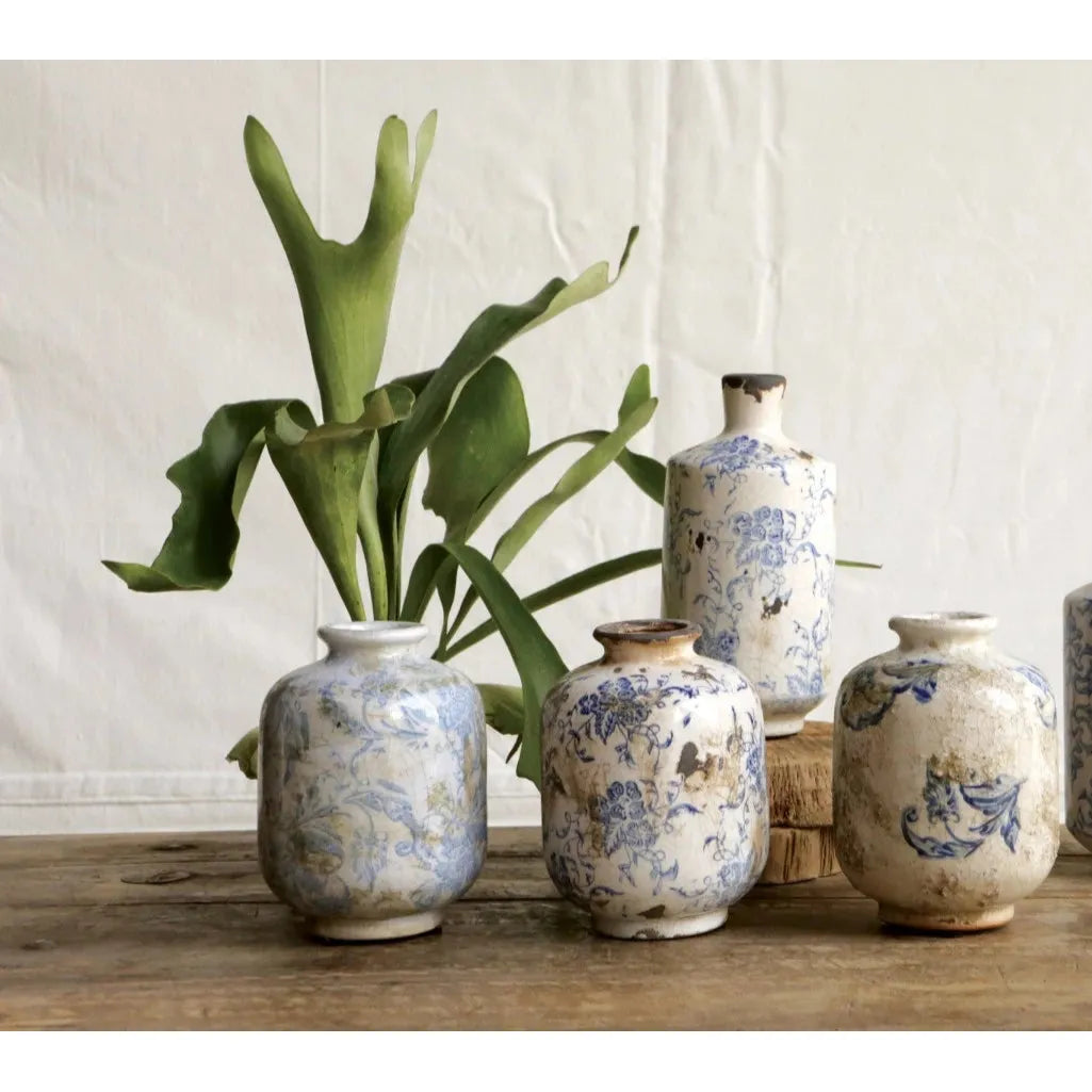 Set of decorative vases with floral patterns on a wooden surface against a neutral background