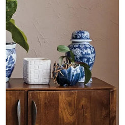 Wooden cabinet with decorative vases, books, and plants against a beige wall.