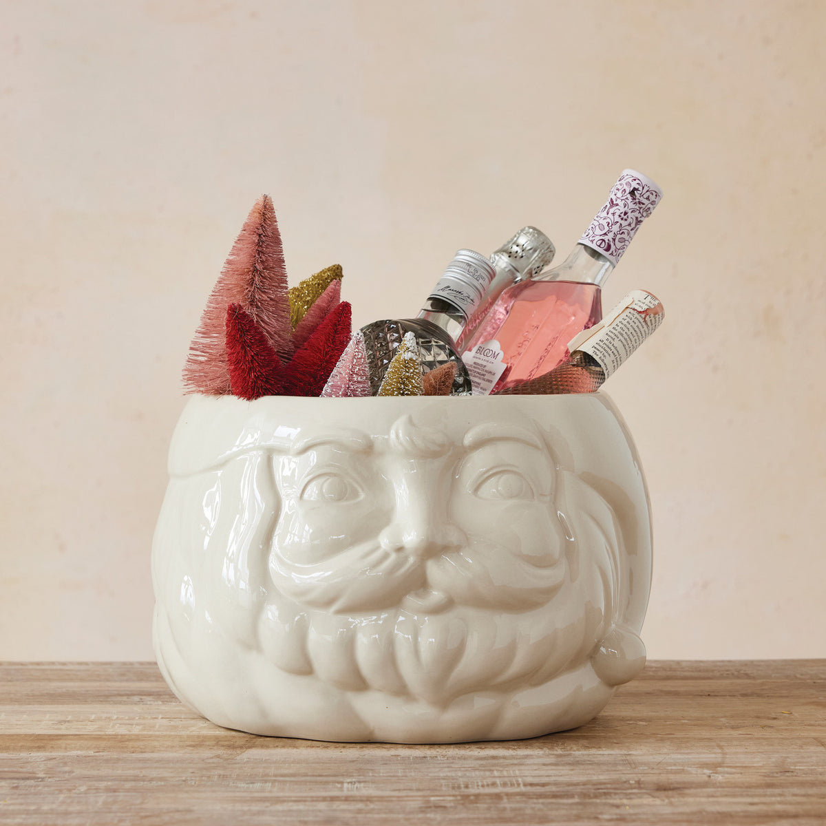 White ceramic container with a face design filled with decorative items on a wooden surface.